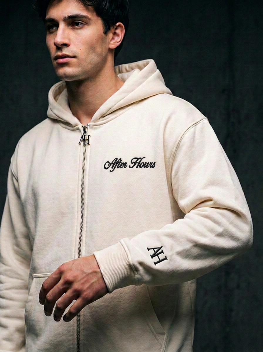 Close-up of the cream After Hours hoodie black embroidery and metal AH zip pull