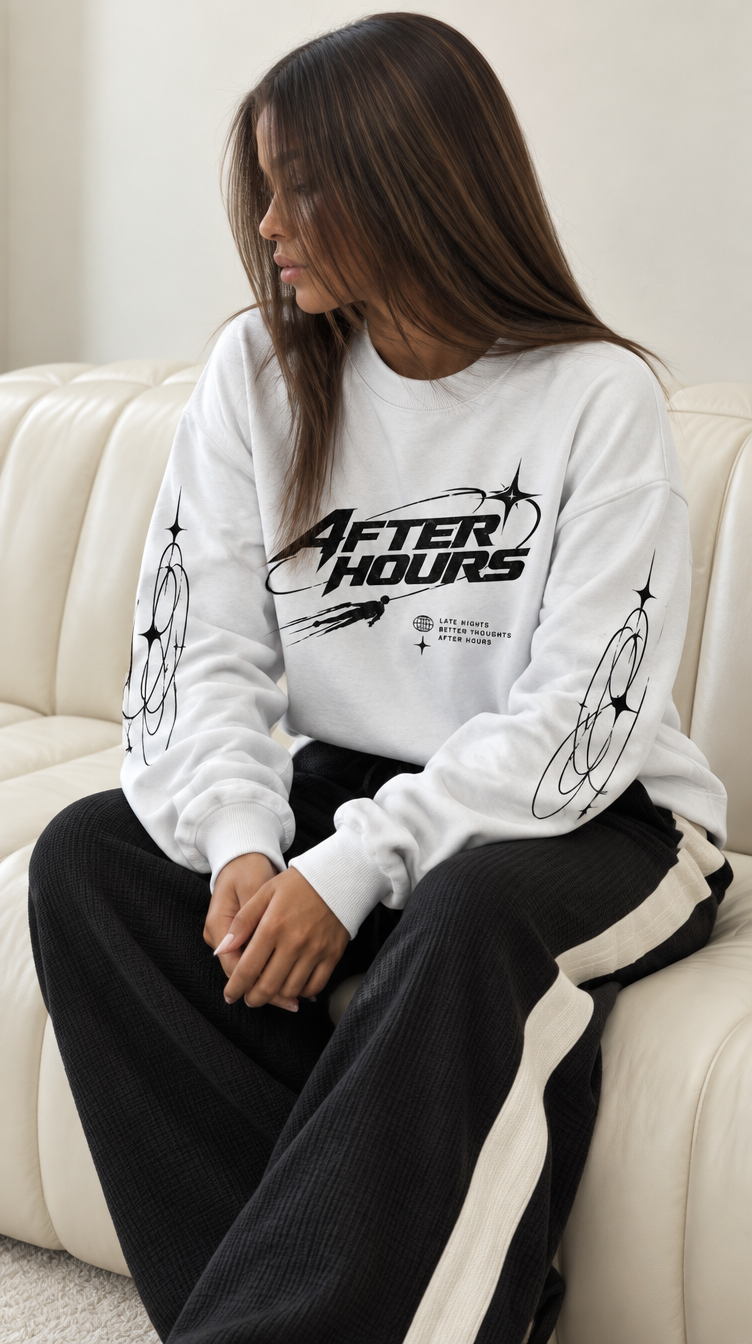 Model sitting on a cream sofa in the heavyweight After Hours Orbit Long Sleeve Tee and black waffle joggers, three-quarter angle