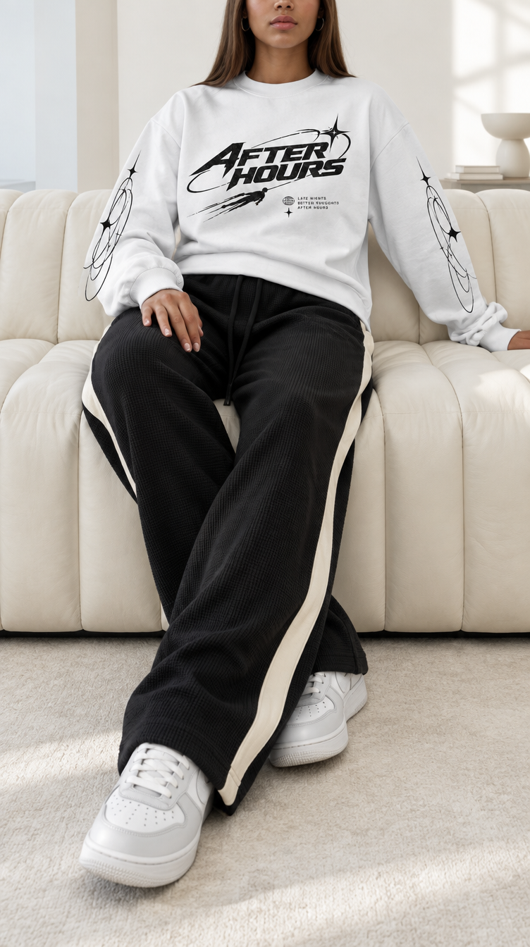 Full-body shot of a model on a cream sofa wearing the heavyweight After Hours Orbit Long Sleeve Tee